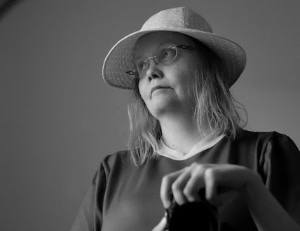 Black and white portrait of a caucasian adult woman looking at the camera, outdoors in fashion clothing.