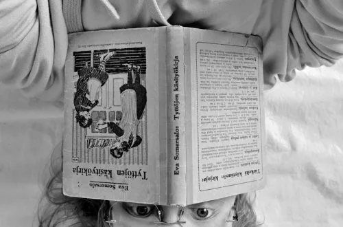 Close-up of a caucasian adult woman reading a book and working on a document indoors