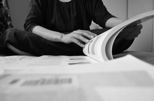 Close-up of a caucasian adult woman reading a book and working on a document indoors.