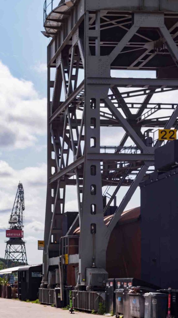 Turun telakan nosturirakenteita ja taustalla vanha Wärtsilän nosturi Aurajoen rannalla sinisen taivaan alla.