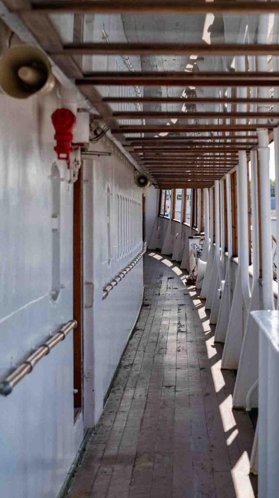 Pitkä puinen käytävä historiallisella Bore-laivalla Turussa, valkoiset seinät ja tummat ikkunat vasemmalla.
