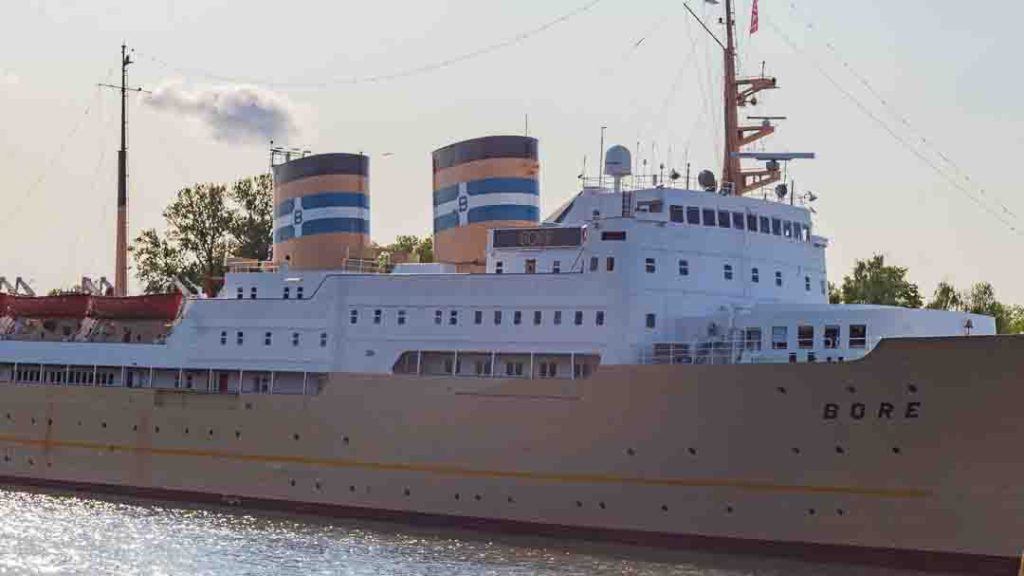 Lähikuva M/S Bore -laivan valkoisesta kyljestä ja kahdesta oranssi-siniraitaisesta savupiipusta Turun Aurajoessa.