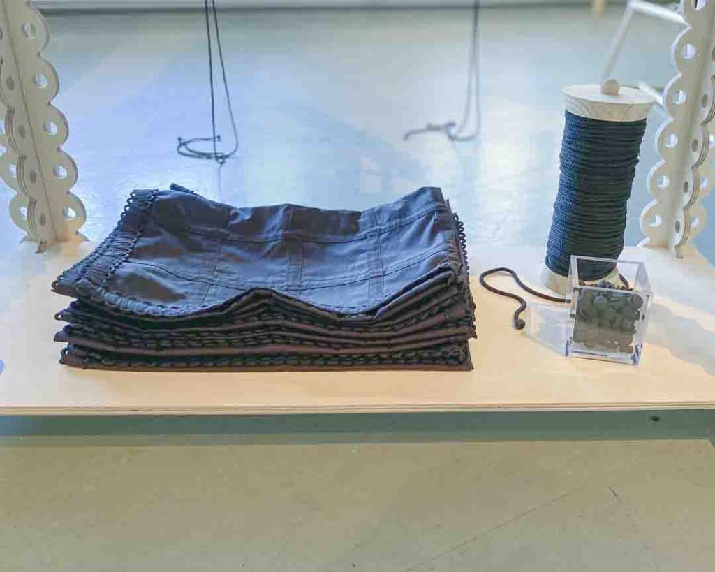 Sofia Ilmosen Formations-näyttelyn vitriini, jossa esillä modulaarisen muodin kankaiden paloja, nappeja ja rakennusosia.