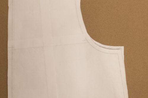 Lähikuva leikatusta kaavan osasta, joka esittää yöpaidan A-linjaista siluettia. Kaava on sijoitettu ruskealle taustalle ja siinä on selkeät linjat ja merkit.