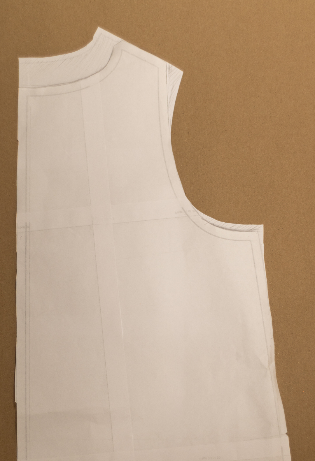 Lähikuva leikatusta kaavan osasta, joka esittää yöpaidan A-linjaista siluettia. Kaava on sijoitettu ruskealle taustalle ja siinä on selkeät linjat ja merkit.