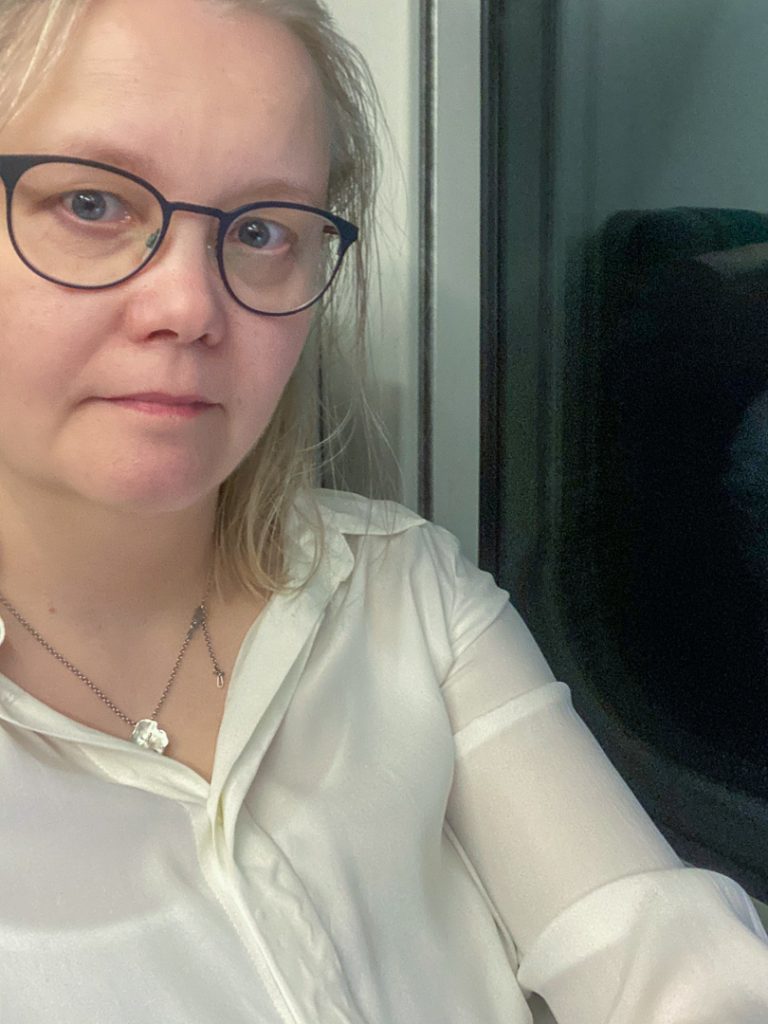 Henkilö työskentelee keskittyneesti läppärillä junassa. Kuva korostaa kiirettä ja työmatkojen todellisuutta.