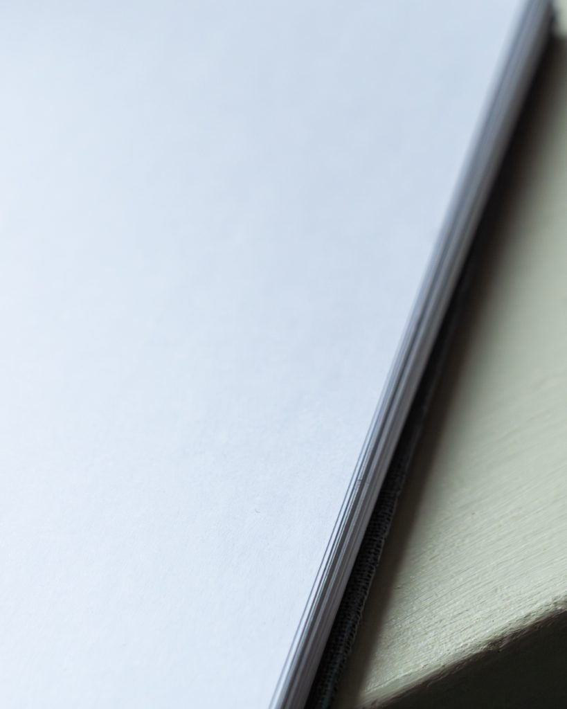 Tyhjä valkoinen paperi pöydällä valaistuna pehmeällä luonnonvalolla.