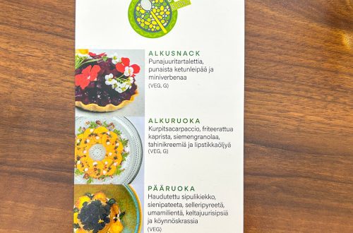 KasvisPro‑menu Taidon opetusraavintolassa; listassa punajuuritartaletti, kurpitsacarpaccio, haudutettu sipulikiekko ja tumma suklaamarkiisi puupöydällä.
