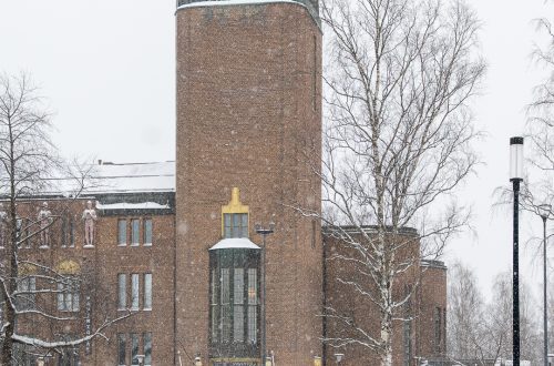 Joensuun kaupungintalo lumisateessa talvella, punatiilinen rakennus ja torni