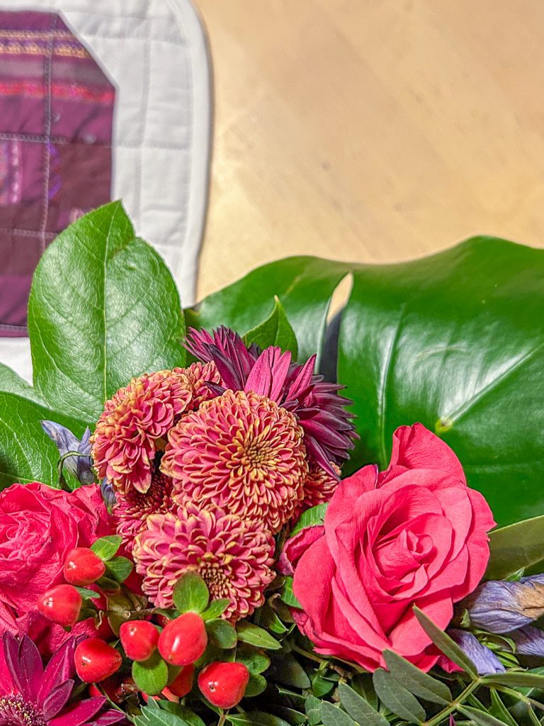 Punaiset gerberat, pinkit ruusut ja krysanteemit vihreillä lehdillä, väripaletti tilkkutyöhön.