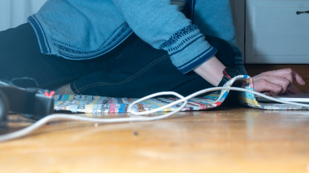 Sunnuntai-illan työhetki kotona – läppäri lattialla ja päällä itse koneneulottu sininen jakku
