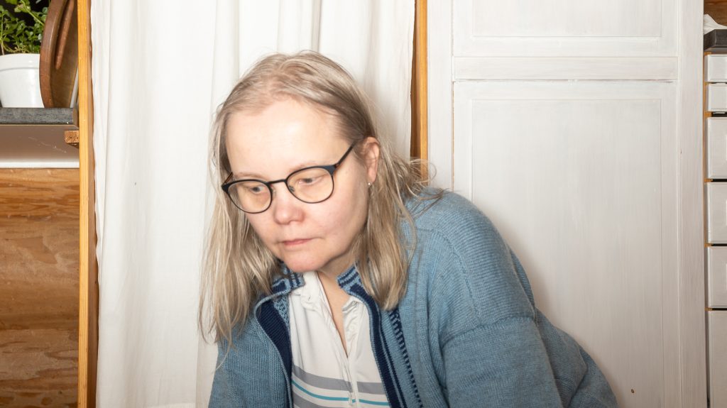 Sunnuntai-illan arki kotona – sivutoiminen päätoimittaja koneneulottu sininen jakku päällä
