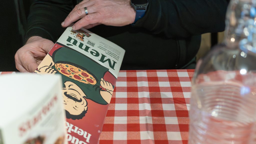 Ravintolan ruokalista pöydällä Turussa – italialaisia annoksia ja viinivalikoima kynttilänvalossa.
