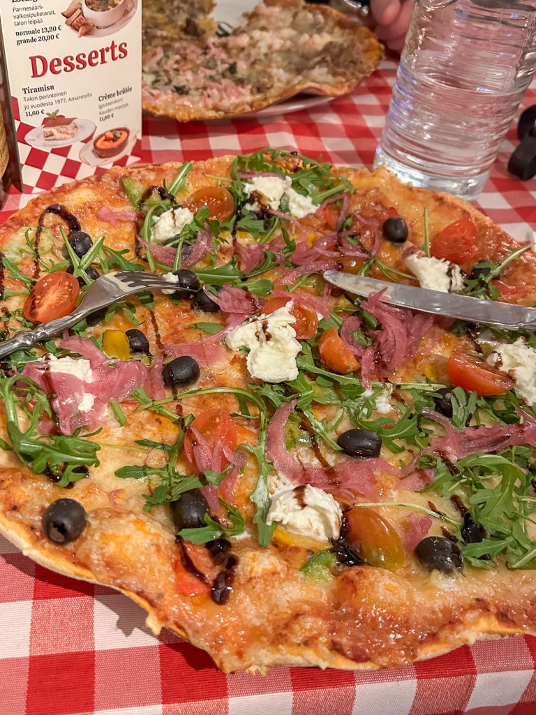 Tuore italialainen pizza ravintolapöydässä Turussa – sulanut juusto ja rucola lähikuvassa.
