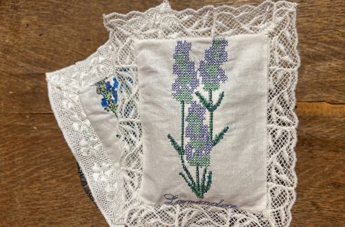 Kaksi valkoista laventelityynyä, joissa on kukkakirjonta ja valkoinen konekirjottu pitsireuna.